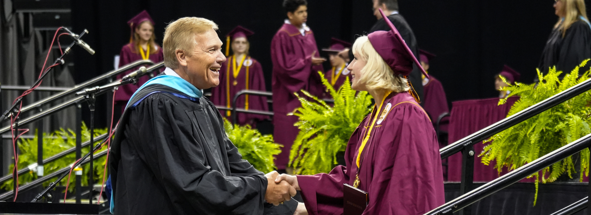 Superintendent Larry Hook shakes the hand of a newly graduated Turpin student